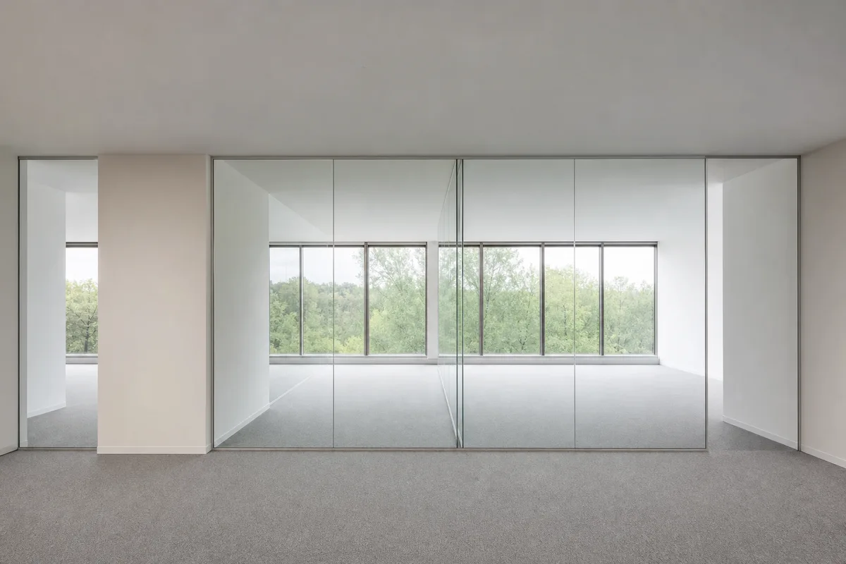 Plateau de bureaux vide avec cloisons vitrées et sol en moquette grise