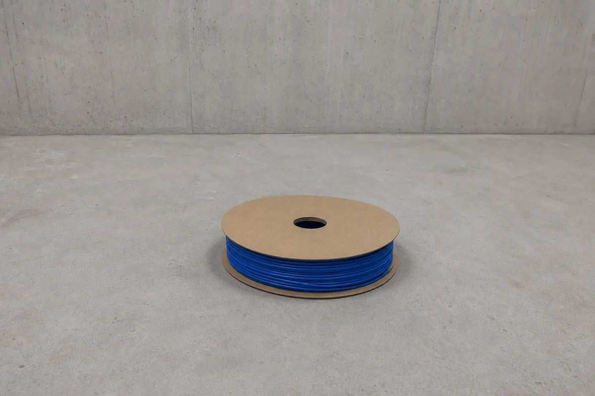 Touret de câble réseau bleu posé au sol dans un local technique vide